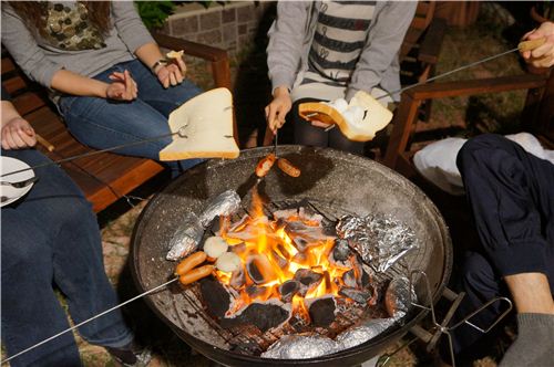 a wild mixture of sausages, fish balls and marshmallow sandwiches on the grill