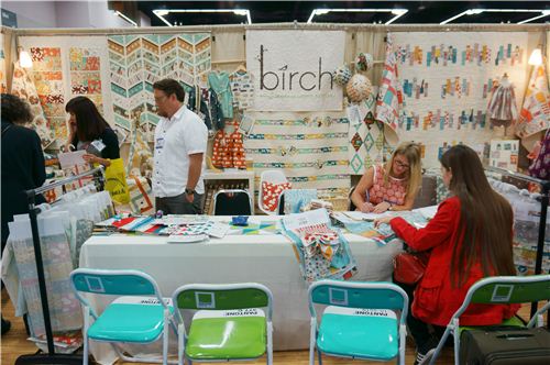 Sandra is ordering fabrics at the birch booth sitting on super cool Pantone chairs