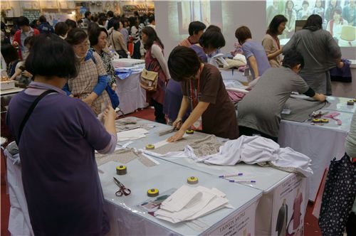 Some women practicing cutting sewing patterns with templates. 